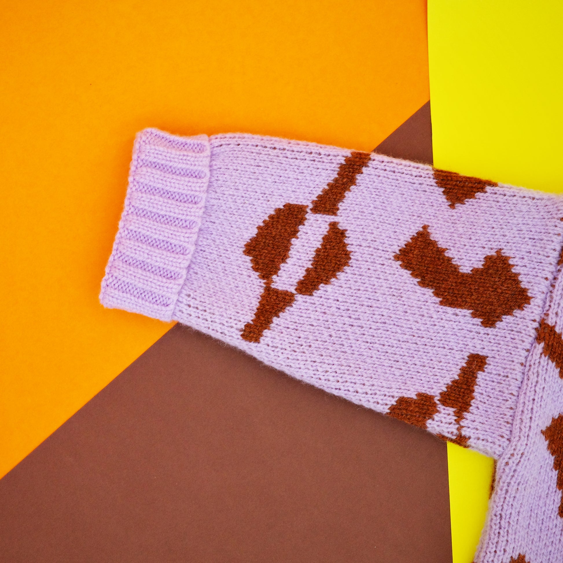 Fold back cuff of lilac and brown wool jacquard baby jumper.