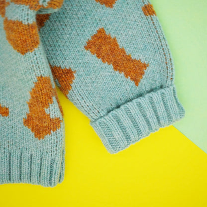 Fold back cuff of mint and orange wool jacquard baby jumper.