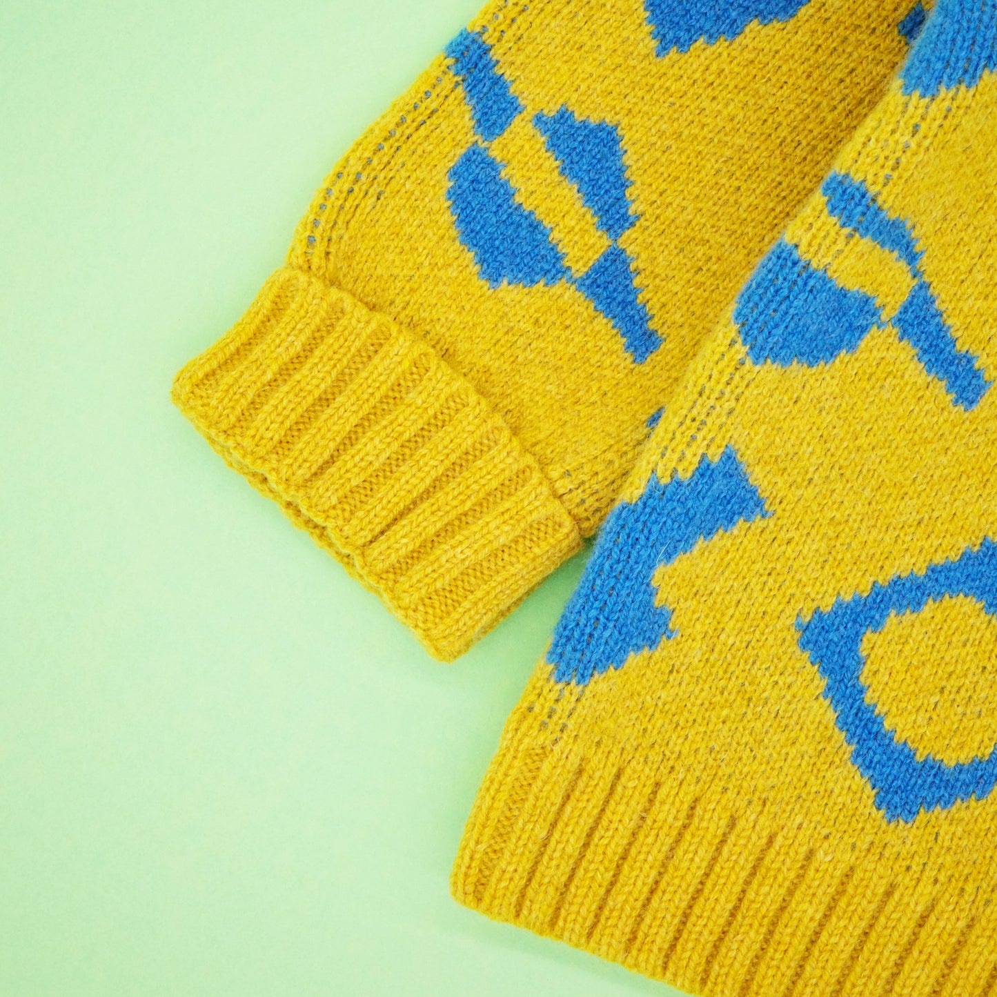 Fold back cuff of children's wool cardigan, in a yellow and blue jacquard.