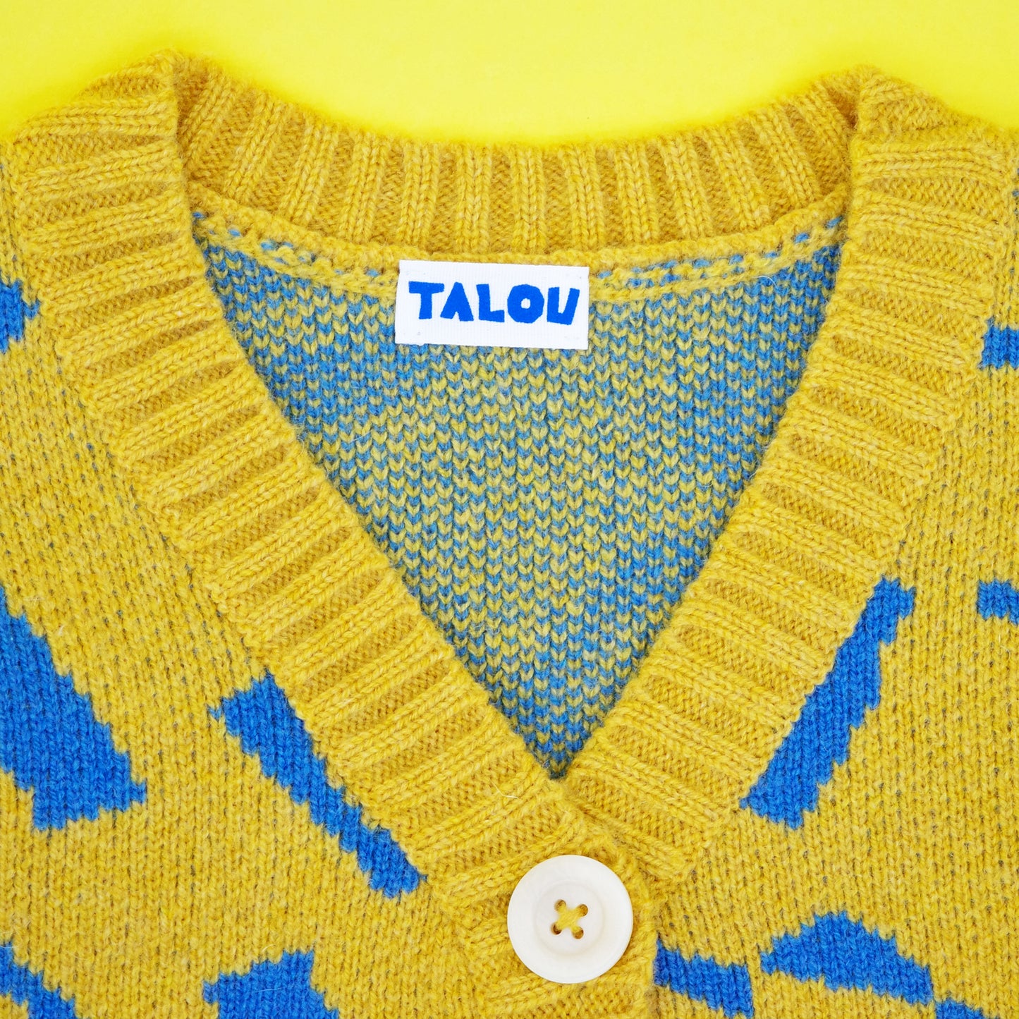 Neckline of children's wool cardigan in yellow and blue jacquard knit.