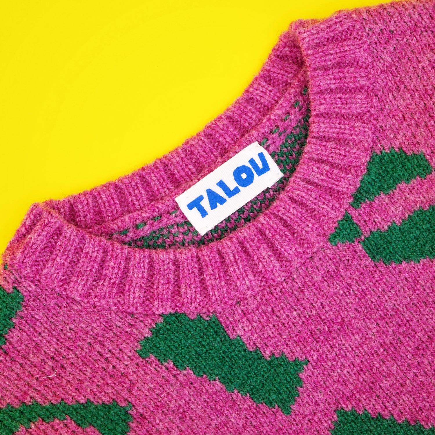 Neckline of children's jumper in pink and green wool jacqaurd.